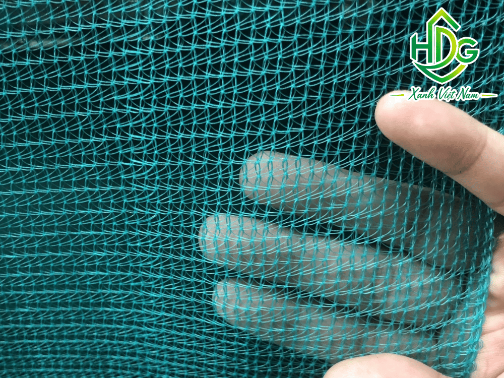 Cận cảnh sợi nhựa, mắt lưới và mép gia cố của lưới xanh che công trình